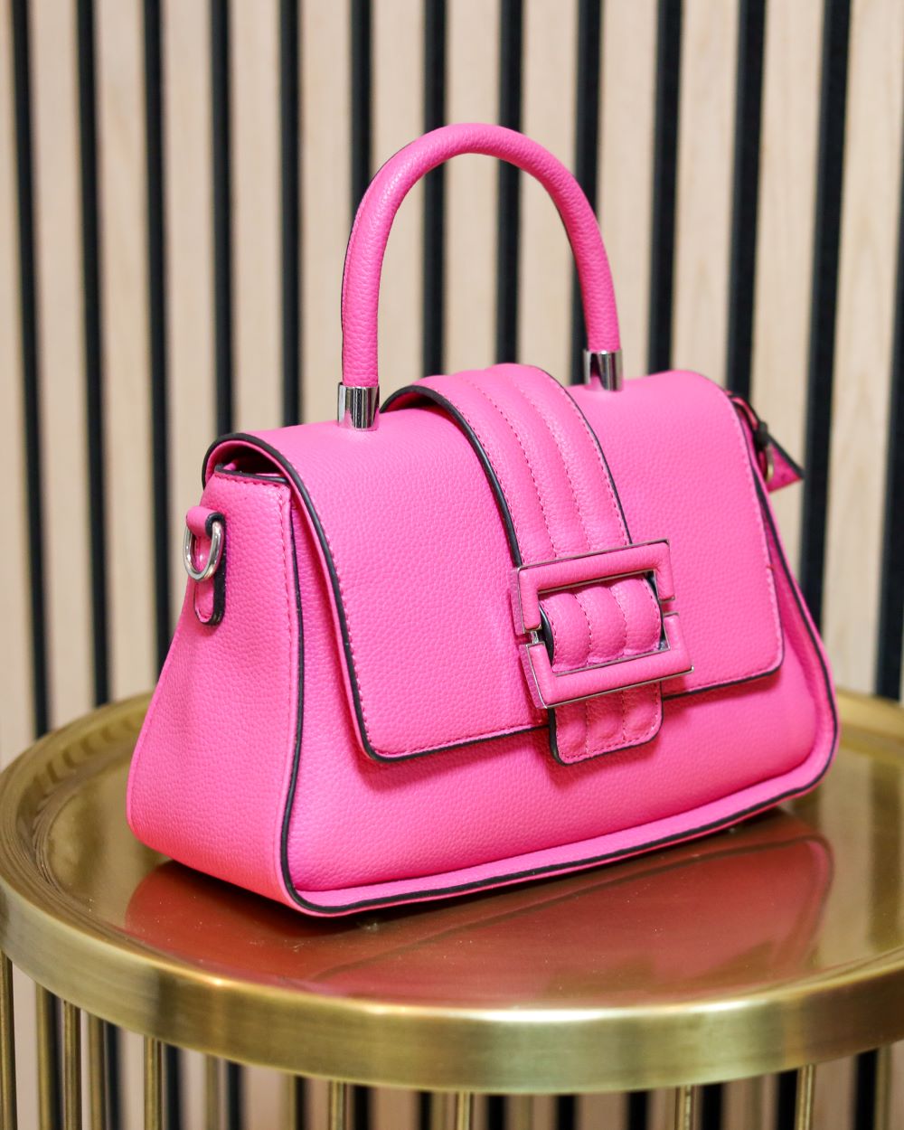 Roze handtas met gesp en handvat.